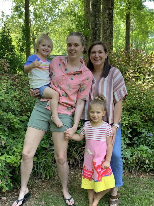 two smiling women holding two young girls
