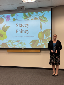 Stacey Rainy holding award in front of projector.